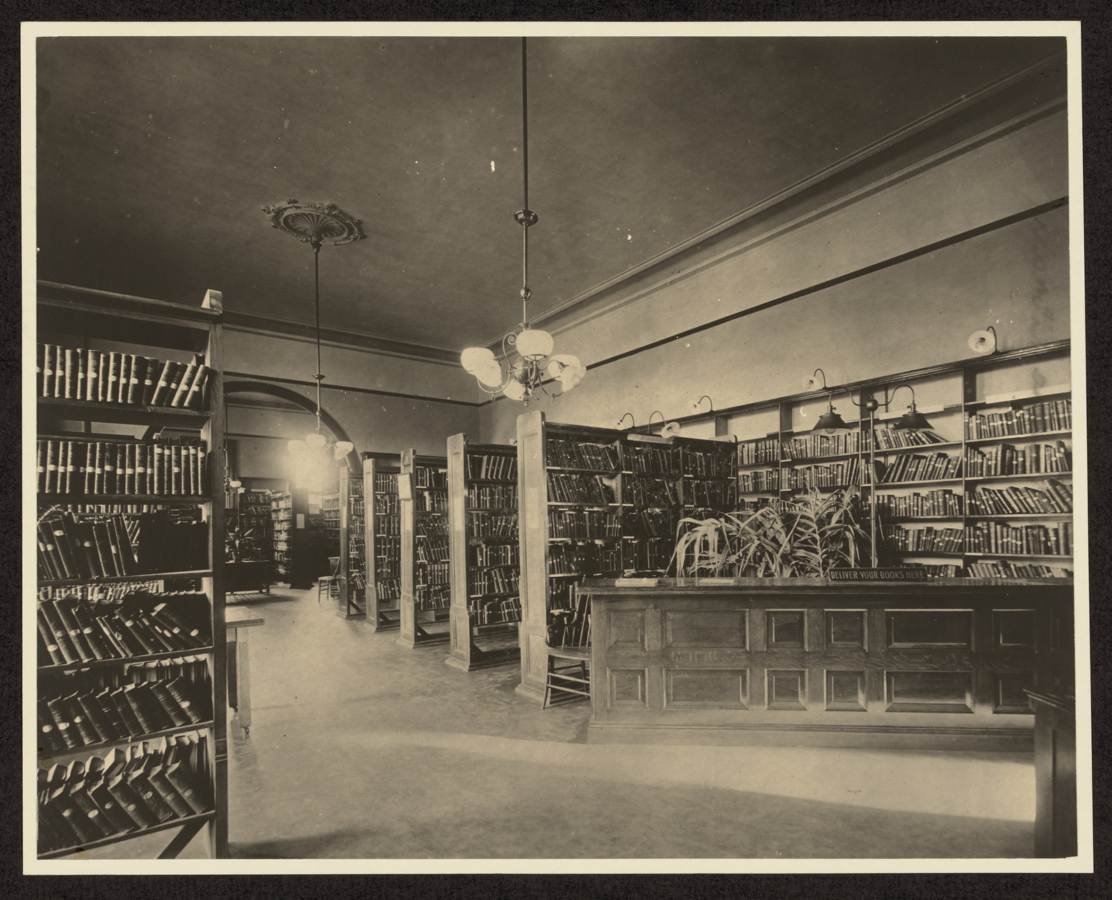 Library interior with bookshelves and a wooden reading desk — historic image