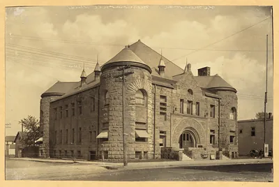 Stone library building with arched entrance, sepia photograph