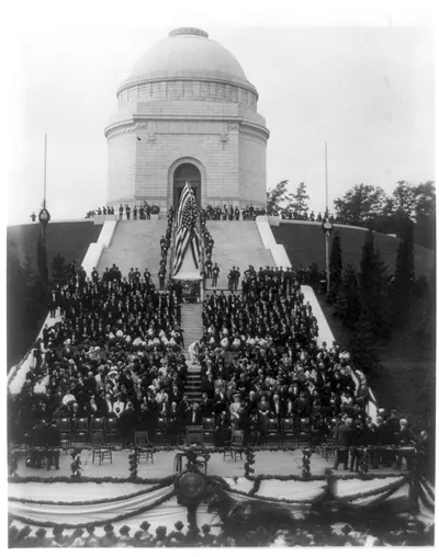 Crowd at a domed monument dedication ceremony with flag