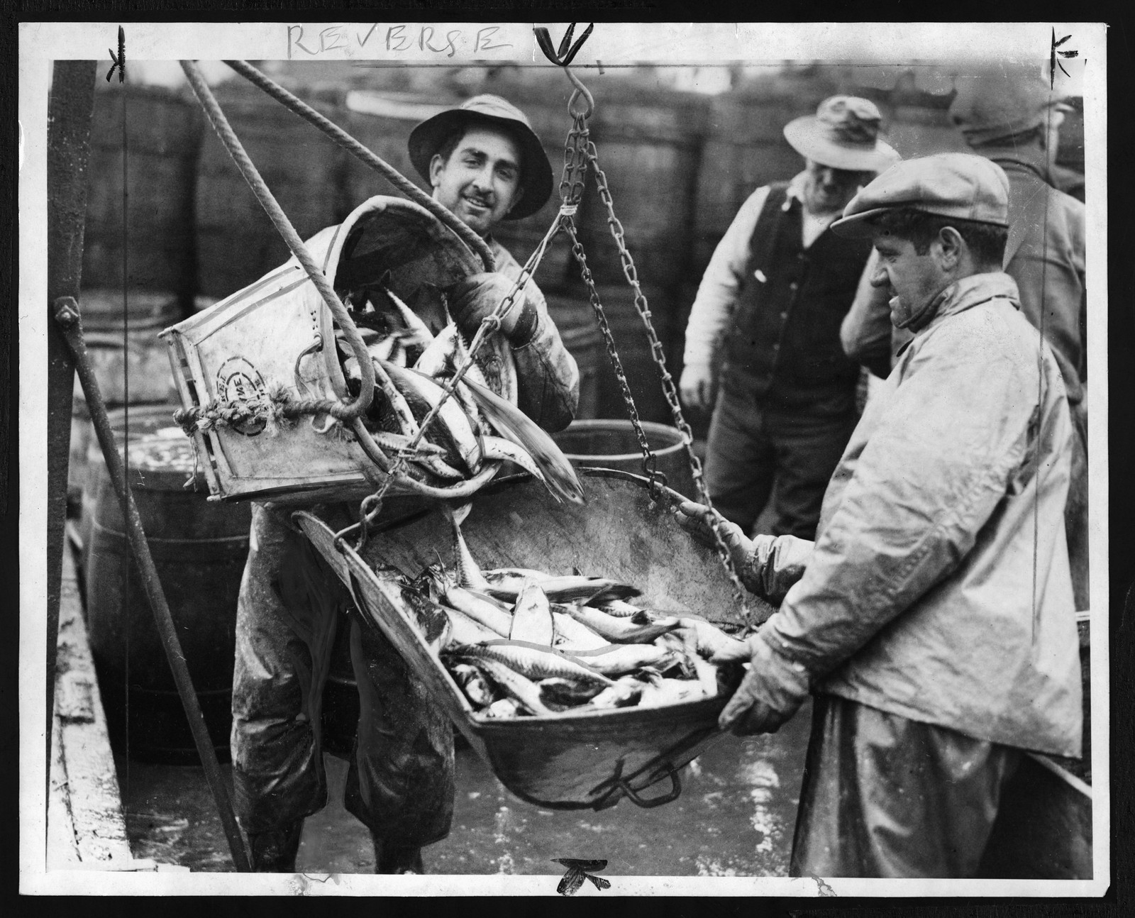Men unloading fish from baskets on a market dock — historic image