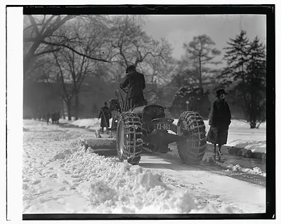 Tractor with chained tires plowing snow on a road