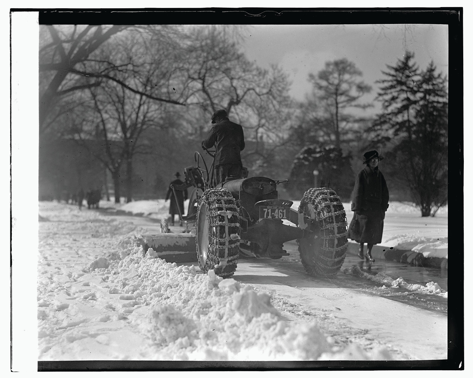 Tractor with chained tires plowing snow on a road — historic image