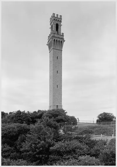 Tall stone tower with crenellated top above trees