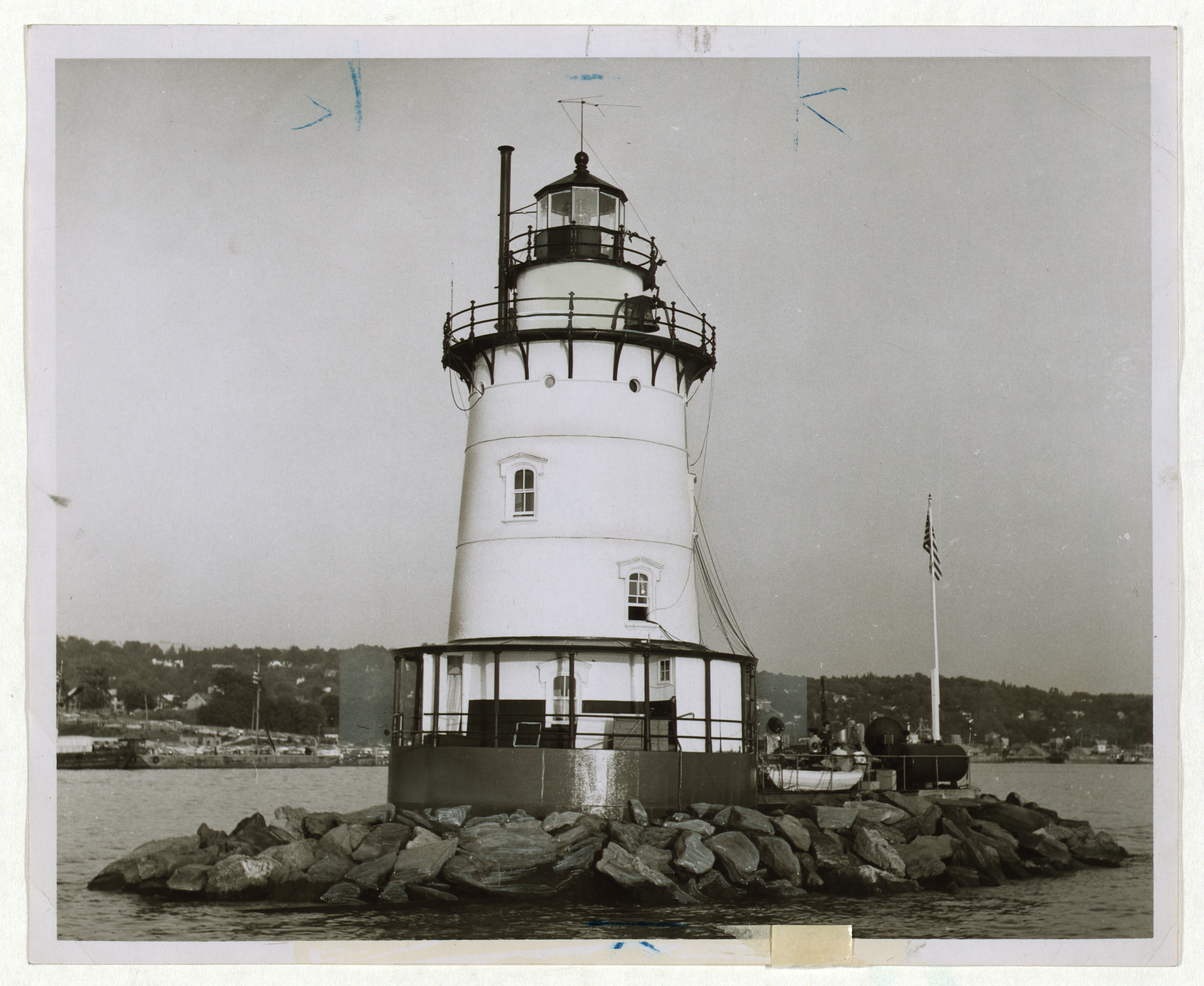 Lighthouse on rocky island in a harbor, black-and-white photograph — historic photograph