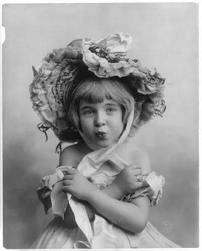 [Little girl, half lgth., facing front, wearing bonnet, with arms folded and lips puckered]