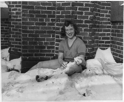 [Pepi Schultz, 19 years old, the German National All-Around Champion in 1928, seated in and rubbing her legs with snow, Chicago, Ill.]