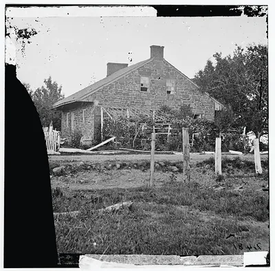 Stone farmhouse with trellis and fence, historic glass-plate photograph