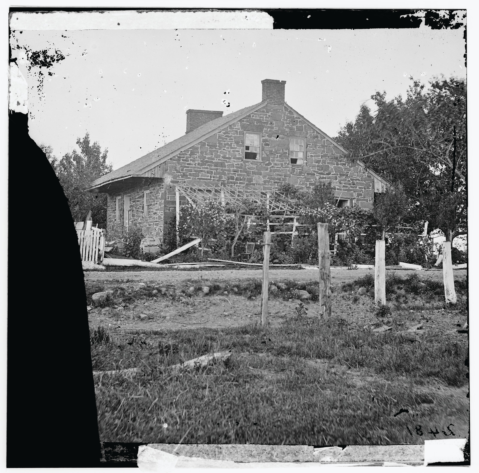 Stone farmhouse with trellis and fence, historic glass-plate photograph — historic photograph
