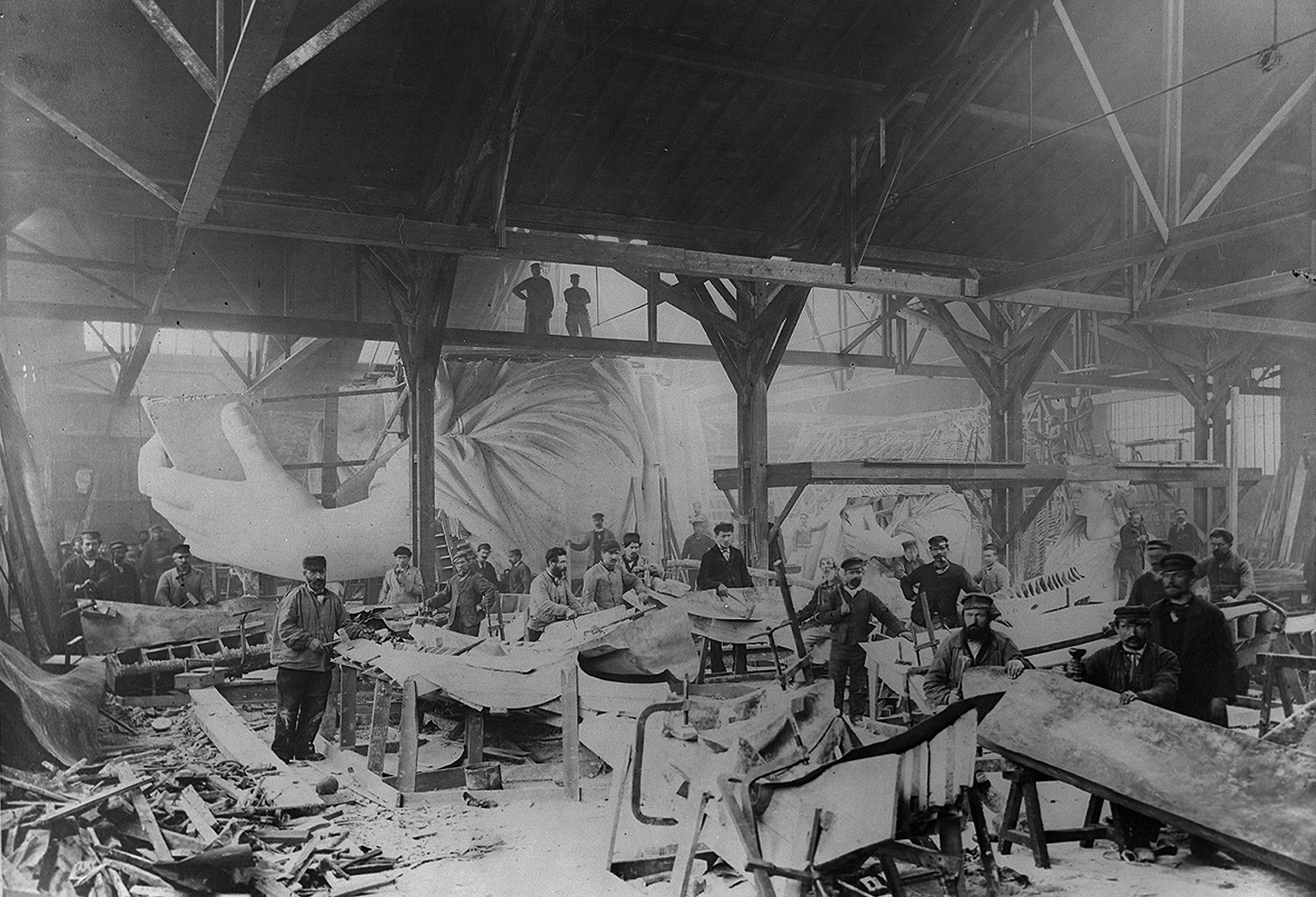 [Workmen constructing the Statue of Liberty in Bartholdi's Parisian warehouse workshop; first model; left hand; and quarter-size head--Winter 1882?], [1882 or 1883] — historic photograph