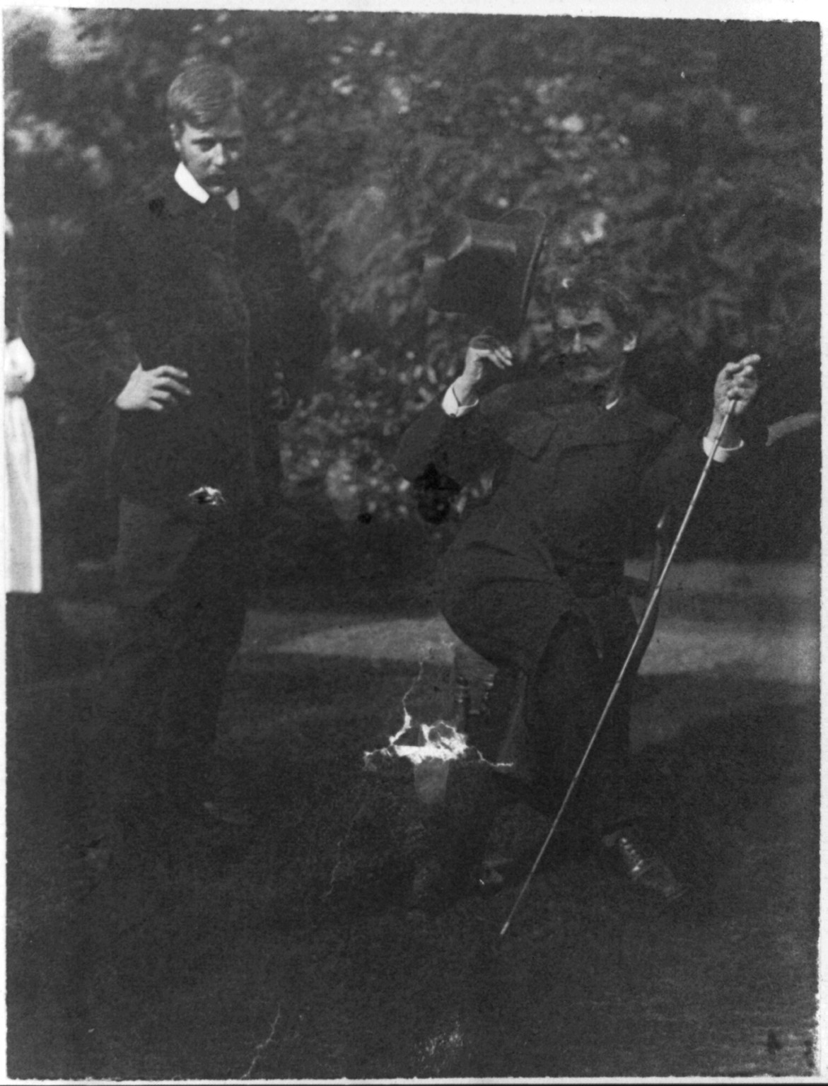 [Whistler seated with Mortimer Menpes standing. Whistler wears the much talked about coat wth cape and curly brimmed hat], [ca. 1885] — historic photograph