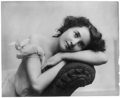 [Young women modeling: Half lgth., seated, head resting on sofa back]