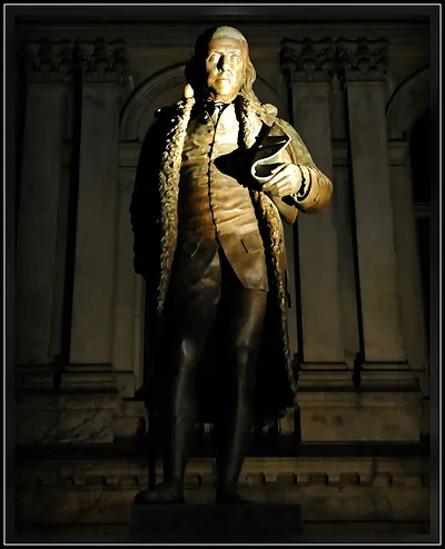 Bronze statue of Benjamin Franklin lit at night