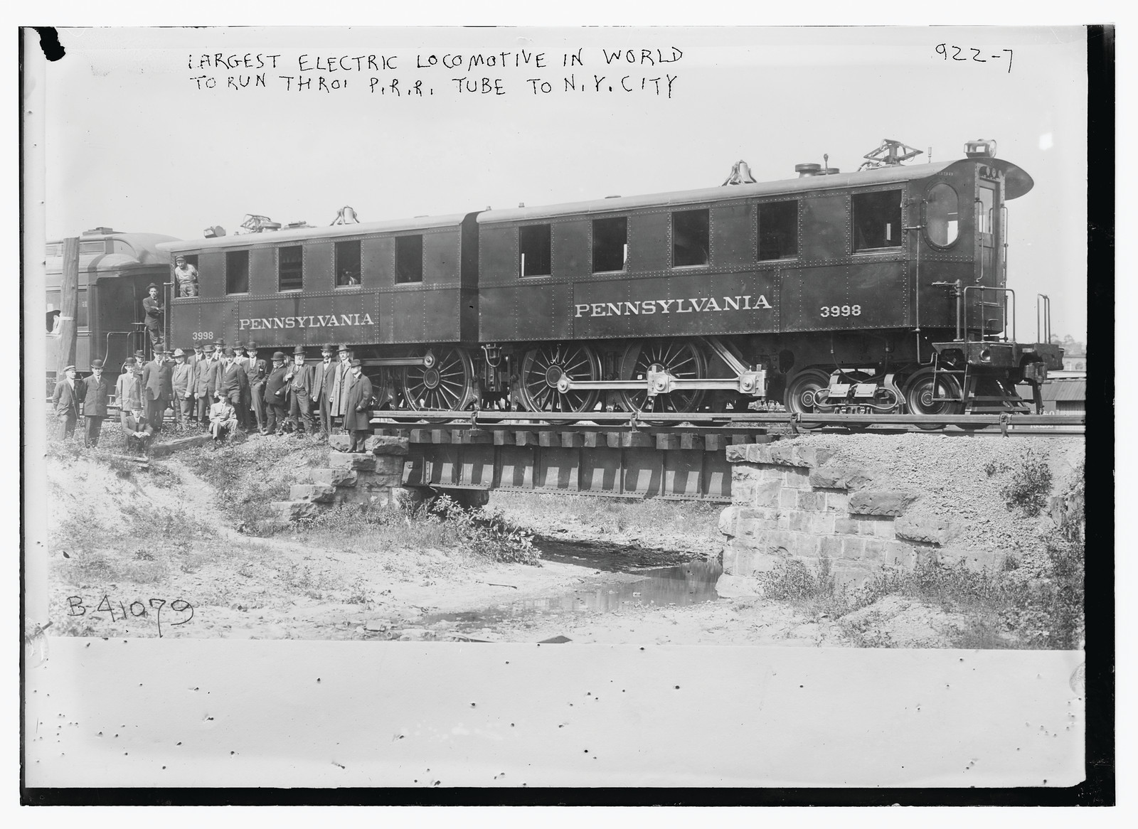 Crowd standing in front of Penn. R.R. car -- the largest electric locomotive in the world, to run through Penn. R.R. tube to N.Y. City, n/a — historic photograph