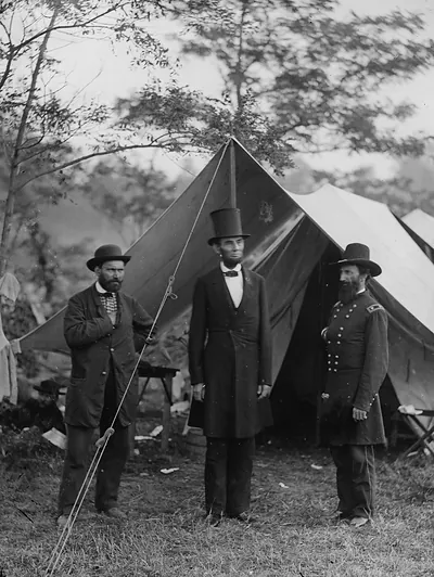 Three men standing before a Civil War army tent