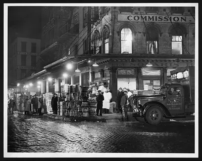 Night view of a produce market with barrels and a delivery truck