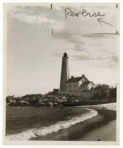 Lighthouse and keeper's house on rocky shore, marked Reverse