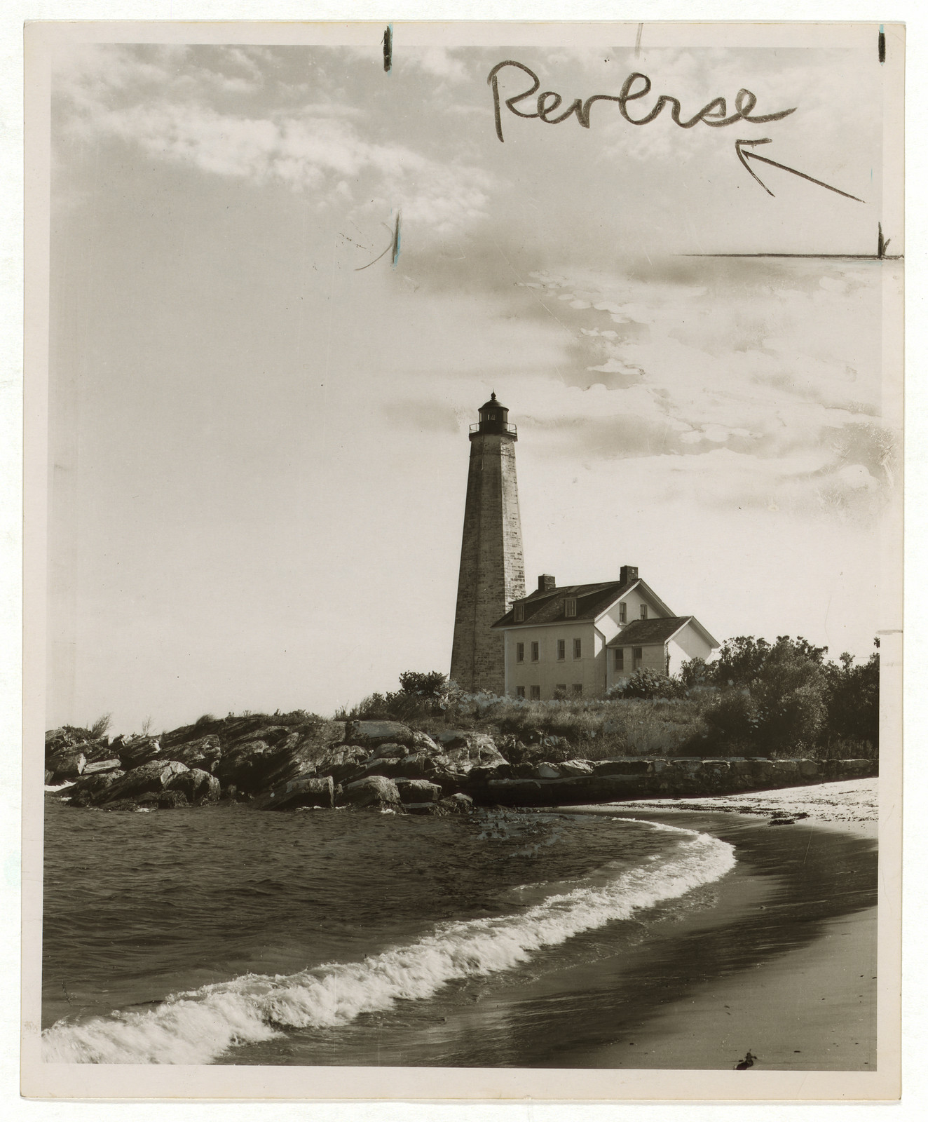 Lighthouse and keeper's house on rocky shore, marked Reverse — historic image