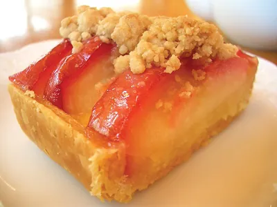 Sliced fruit crumble tart on a white plate