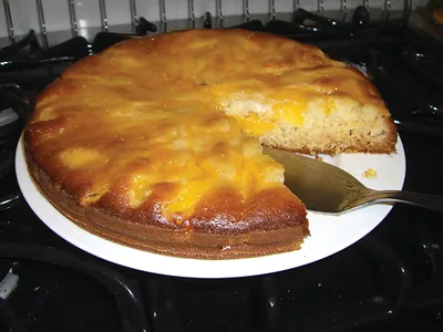 Upside-down fruit cake with a slice cut on a white plate