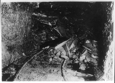 [Dead (?) coal miner under rock after cave-in in tunnel]
