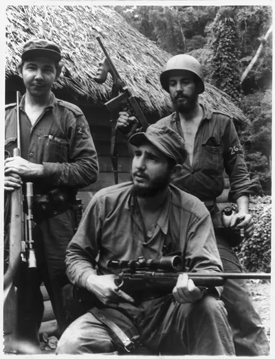 Armed for action. Rifle-bearing Cuban rebel leader Fidel Castro, seated, is backed up by two armed followers at their Sierra Maestra mountain hideout in eastern Cuba's Oriente Province