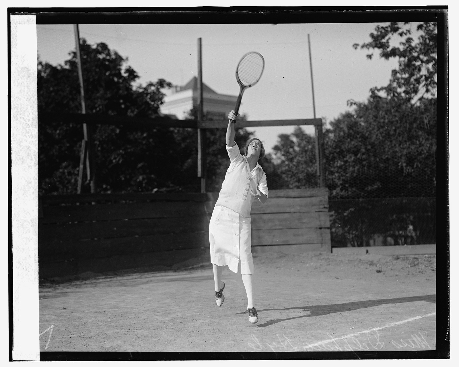 Woman tennis player mid-swing on outdoor court, vintage photograph — historic photograph