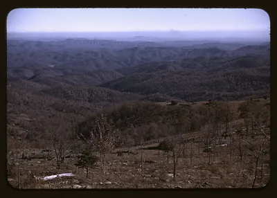 Hazy forested mountain ridges viewed from a bare hillside