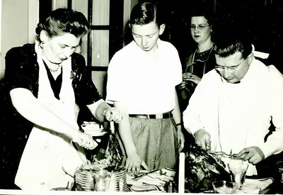 Family carving a roast turkey at a holiday table