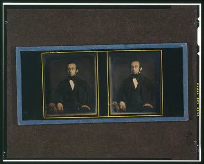 [Unidentified man, three-quarters length, seated, with arm resting on table with tablecloth]