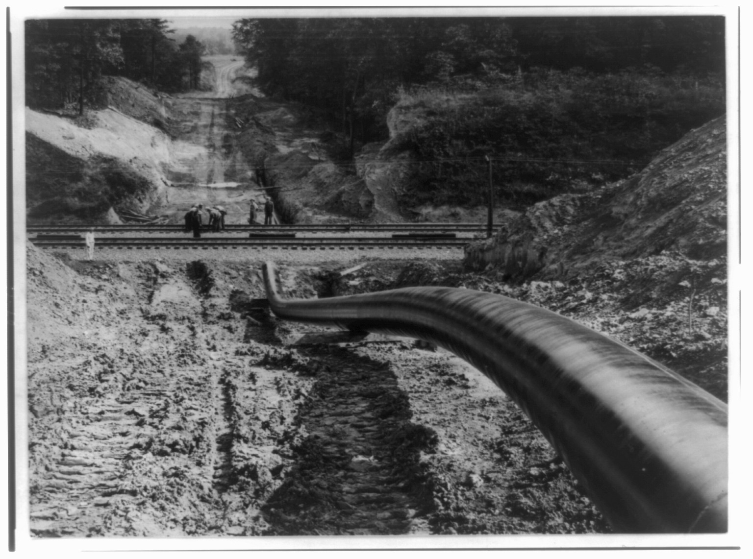 [The Big Inch pipeline under construction: The pipe going under railroad and up hill], [between 1942 and 1943] — historic photograph