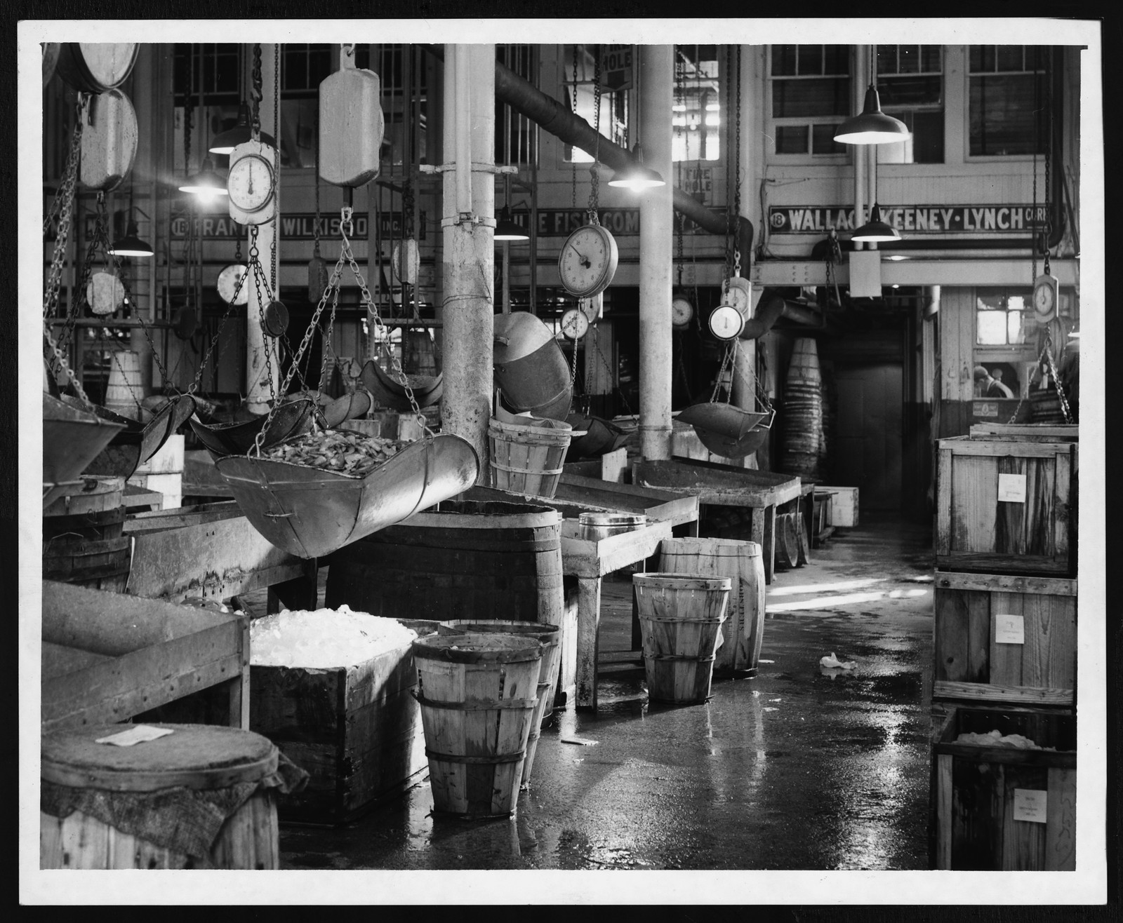 Interior view of a fish market with hanging scales and barrels — historic image