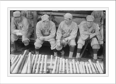 Red Sox baseball players seated in dugout with bats