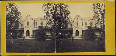 Stereograph of a two-story building with figures on lawn