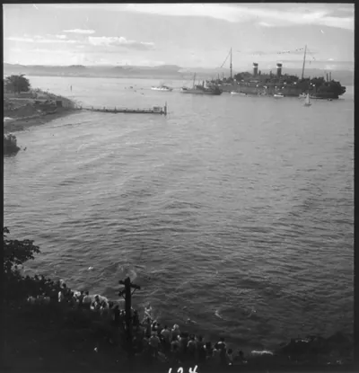 [View of crowd on shore watching passing ship, Puerto Rico]