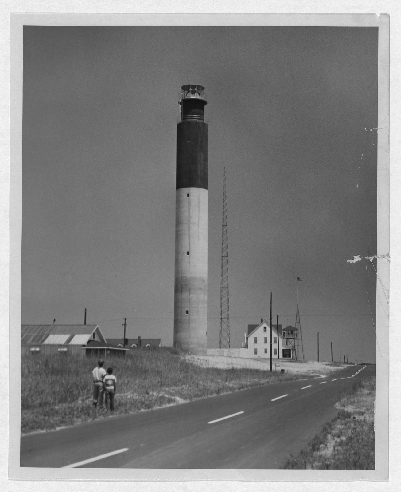 Two boys standing by a highway looking at a lighthouse — historic image