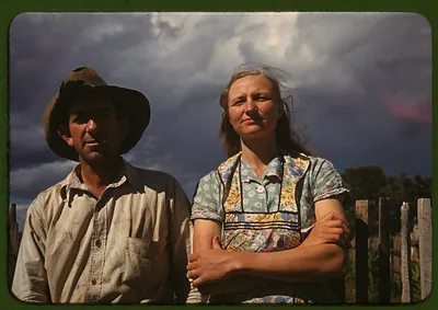 Farm couple standing by a fence under a stormy sky