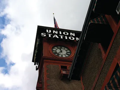 Union Station clock tower with flag against cloudy sky