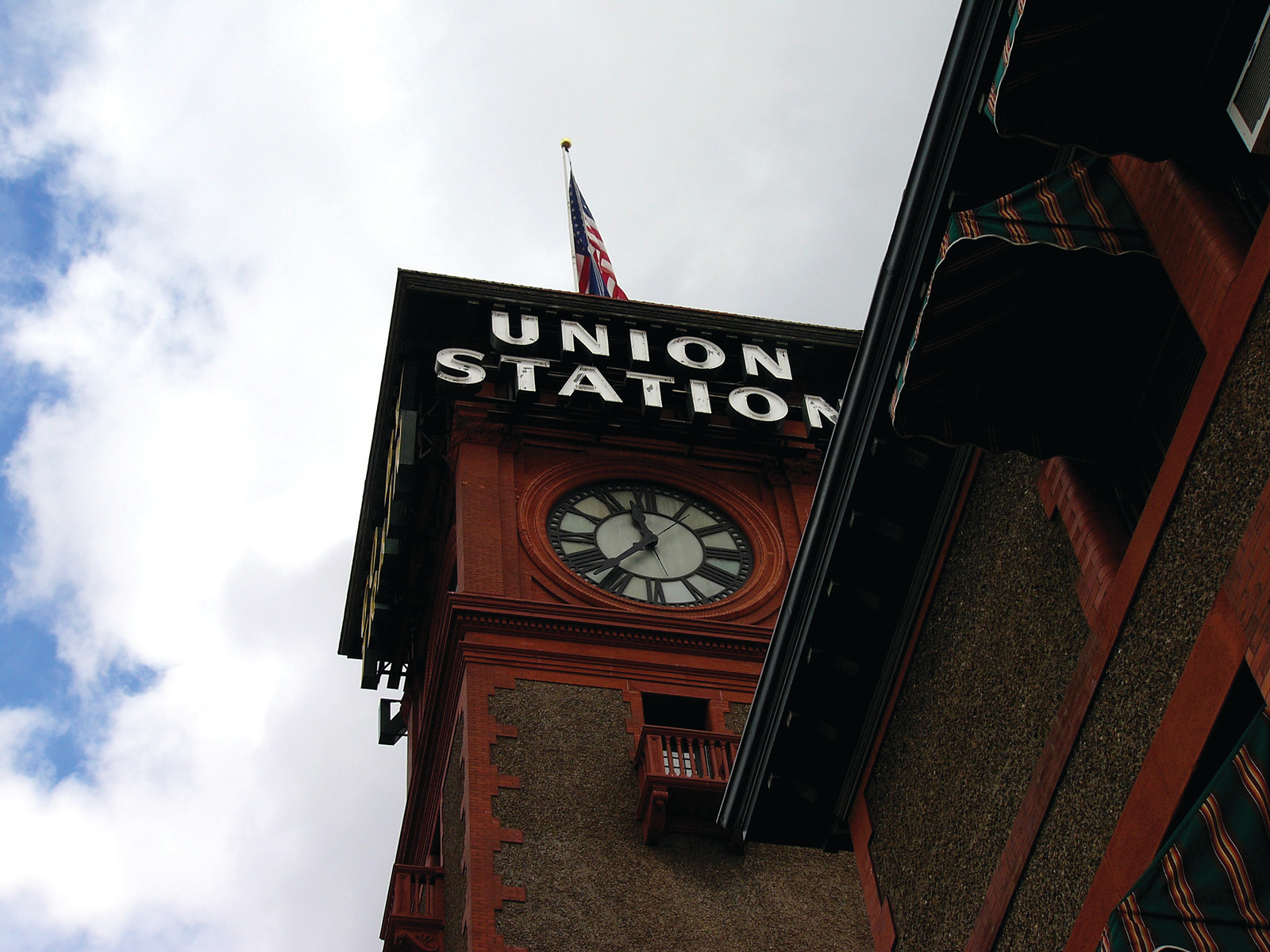 Union Station clock tower with flag against cloudy sky — historic image