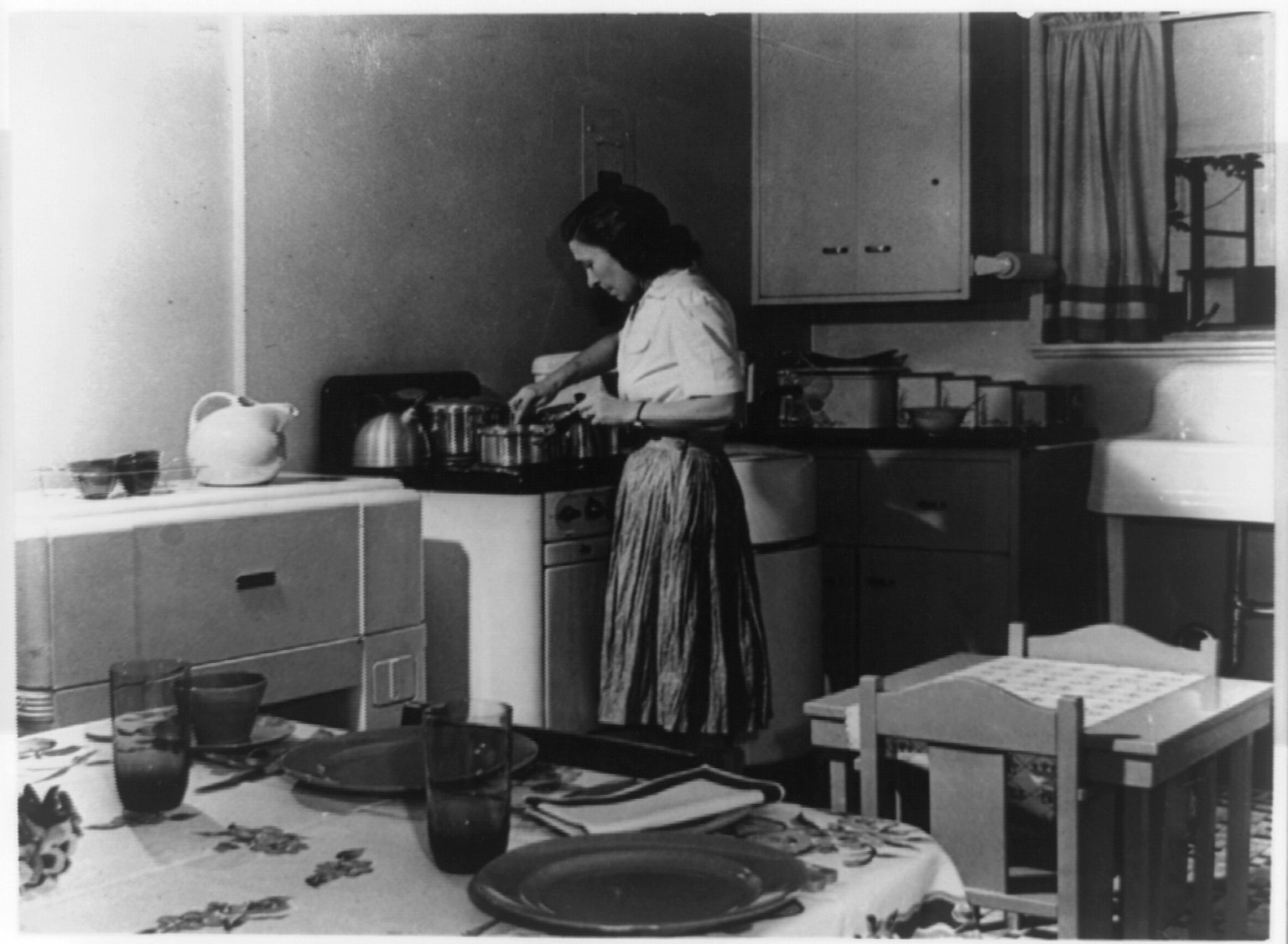 [Housewife preparing dinner in compact kitchen in Greenbelt, Maryland], [between 1940 and 1944] — historic photograph