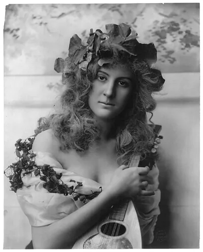 [Young woman modeling: Half lgth., vines on head around shoulders, holding mandolin]