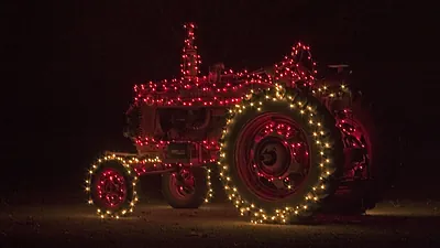 Red tractor decorated with Christmas lights at night